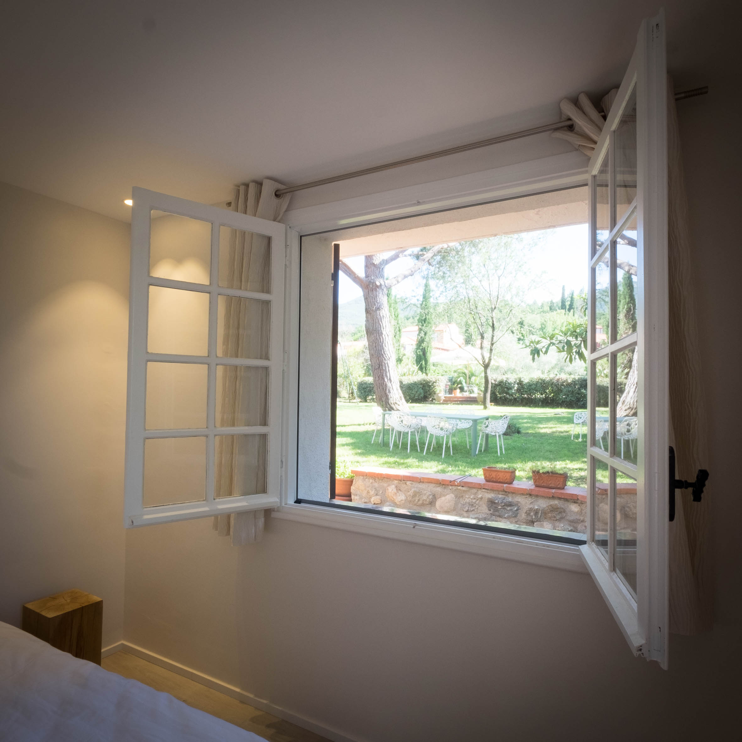 Ventana abierta de la Chambre Olivier con vistas al jardín y los pinos