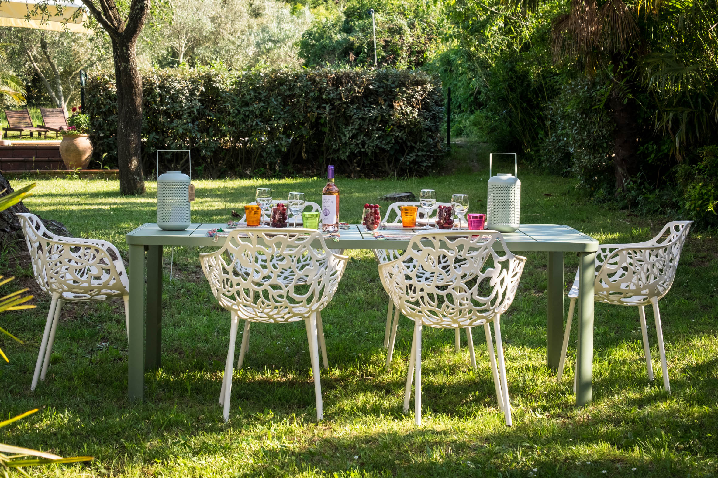Garden table with white chairs under the trees at Villa Alosa