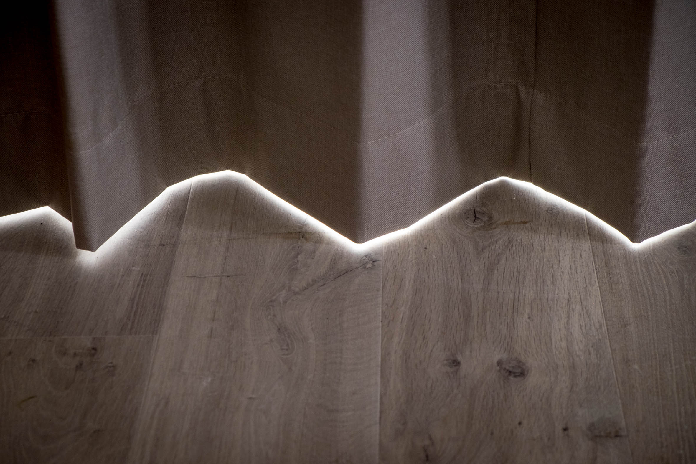 Detalle de madera ondulada iluminado con una suave luz LED en un dormitorio de Alosa Terrace