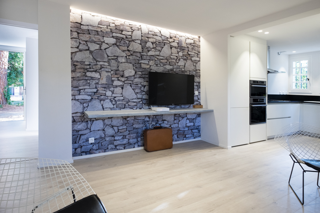 Salón de Alosa Terrace con pared de piedra y televisor