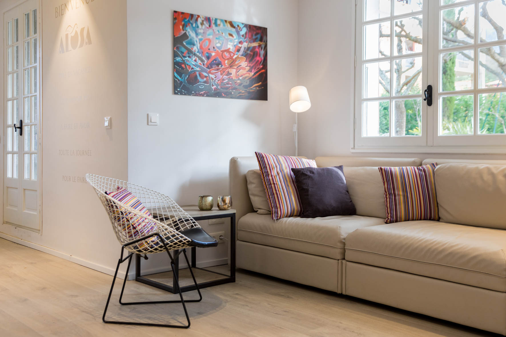 Zona de estar de Alosa Terrace con sofá beige y silla de alambre