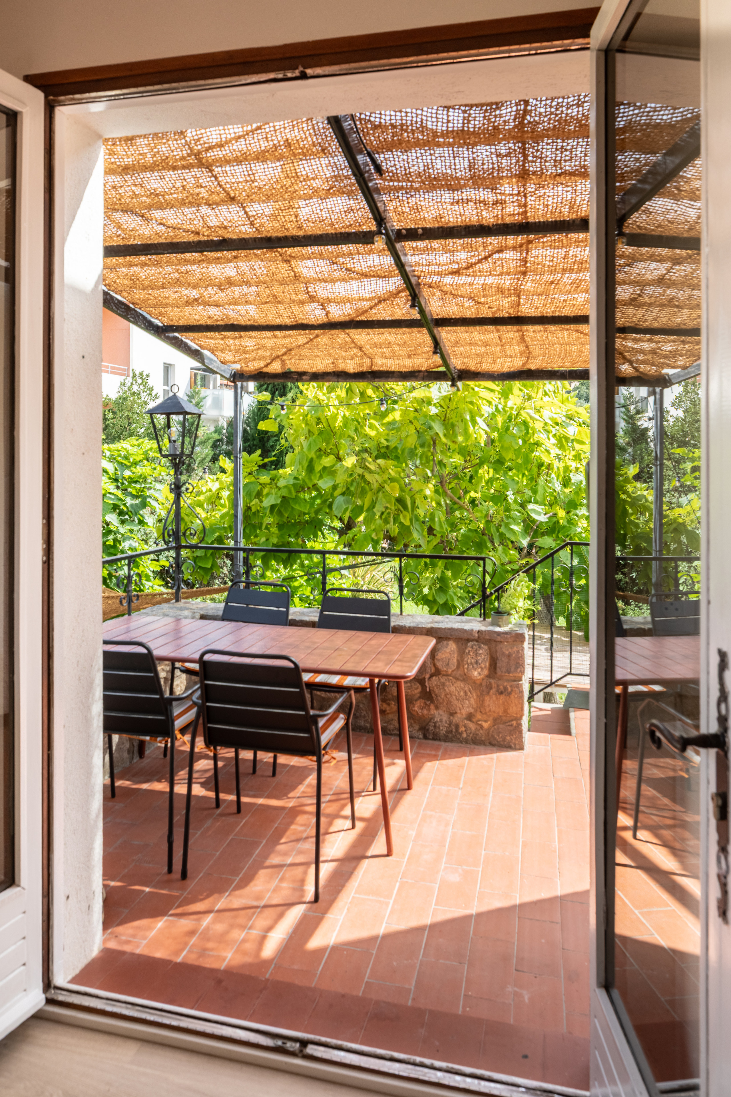 Offene Türen von Alosa Balcon zur Terrasse unter der Schilfpergola