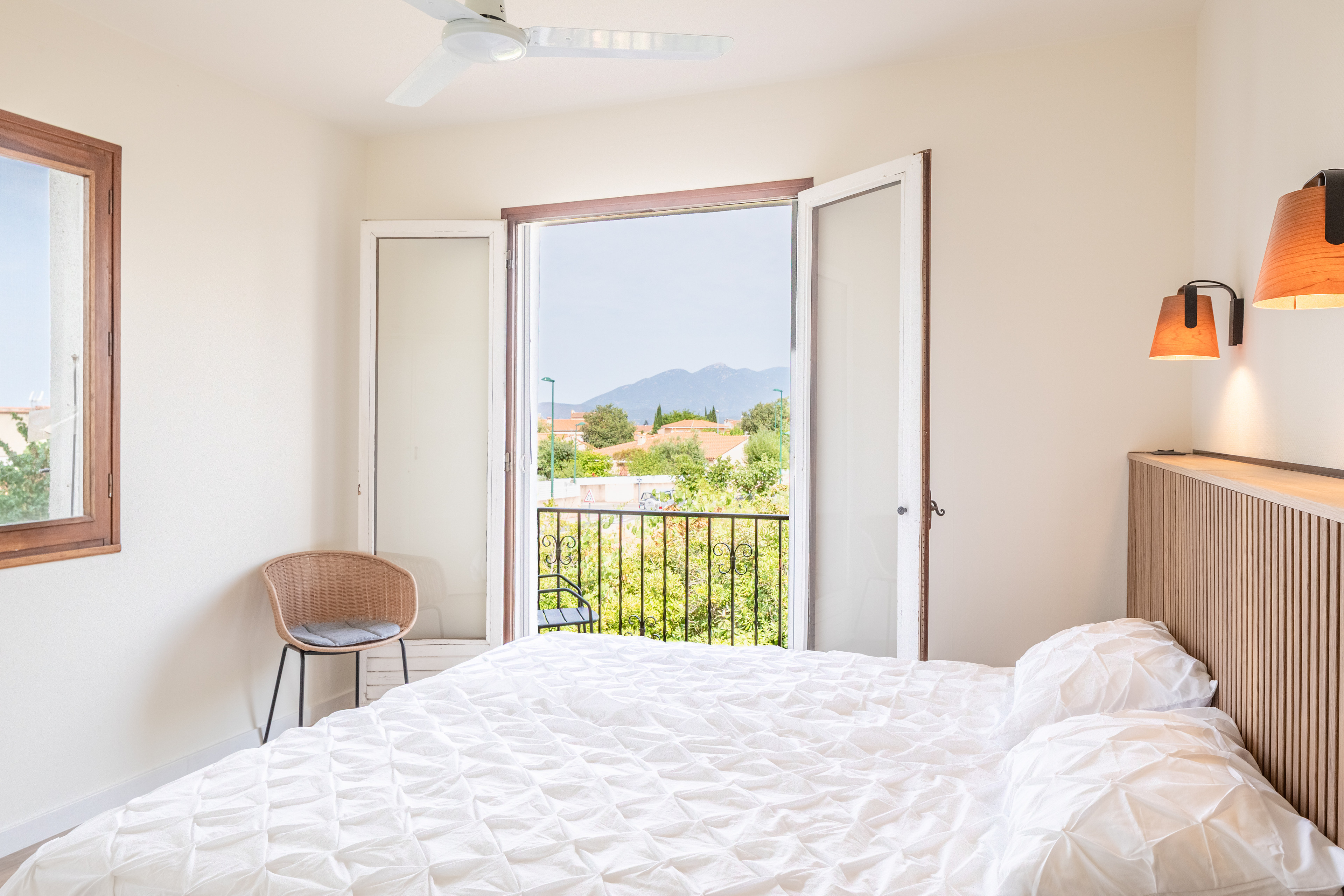 Néoulous, ein Doppelzimmer in Alosa Balcon mit Kopfteil aus Holz und offenen Türen zum Balkon